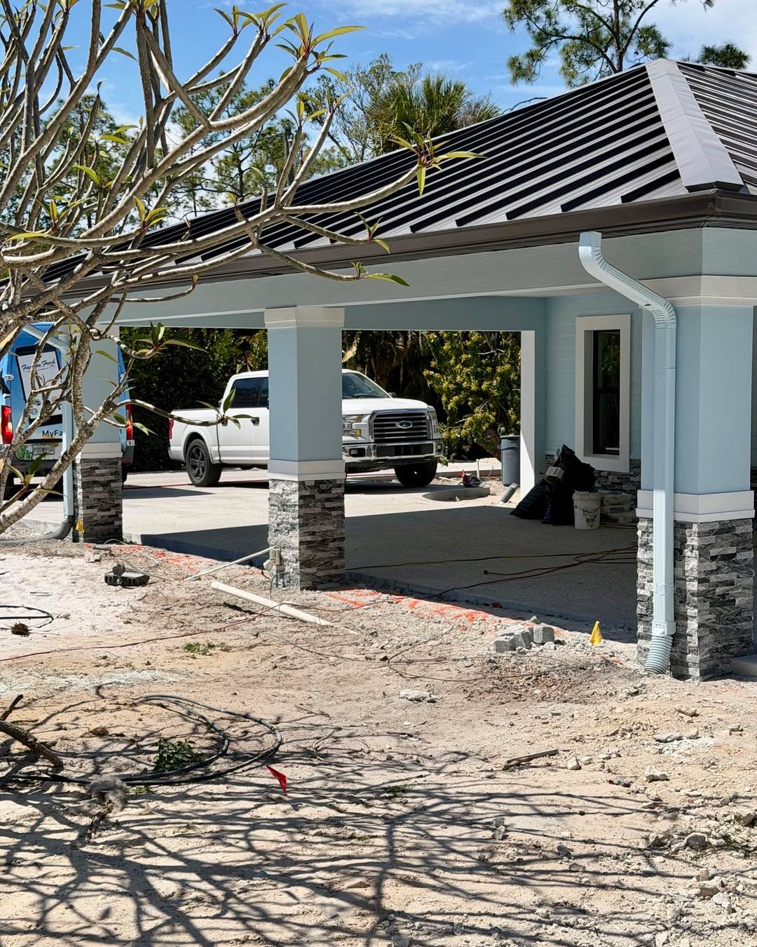 Custom build in progress — stone columns and metal roof