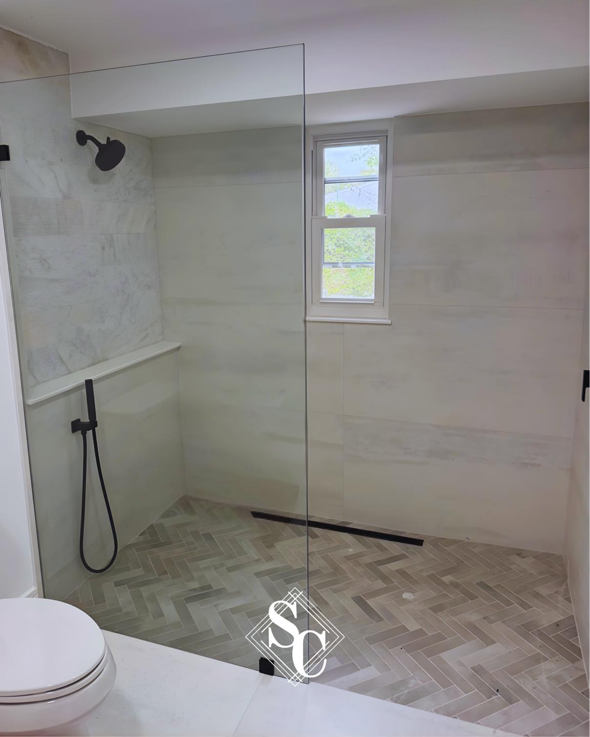 Marble shower with herringbone tile floor